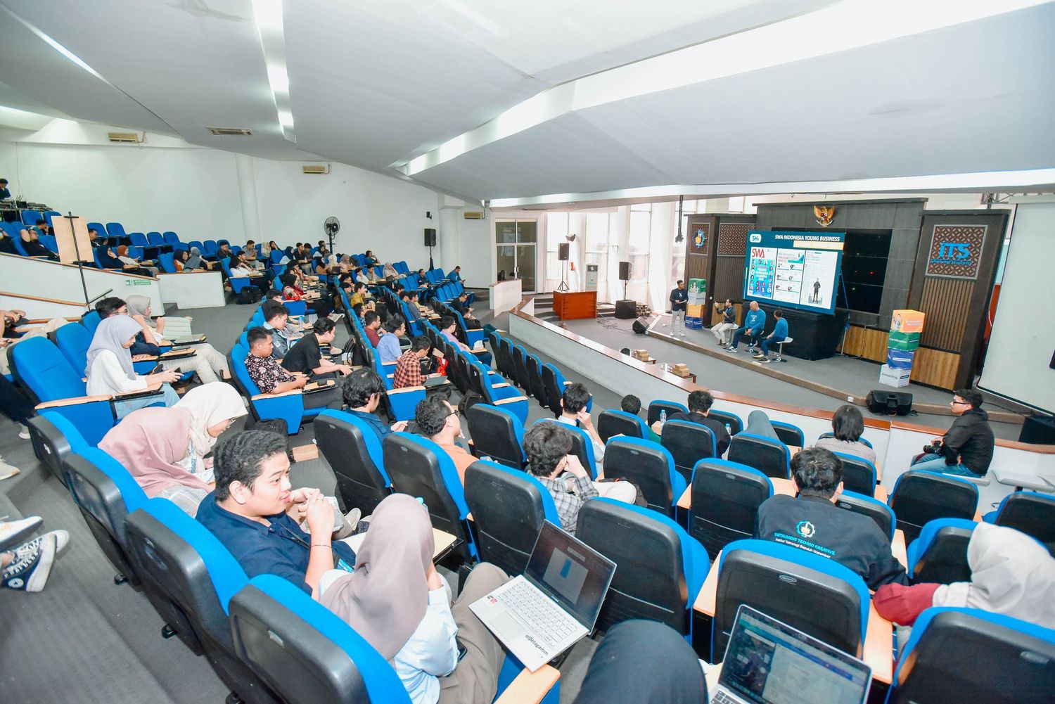 Students seated in rows at desks in a classroom during a lecture or study session.