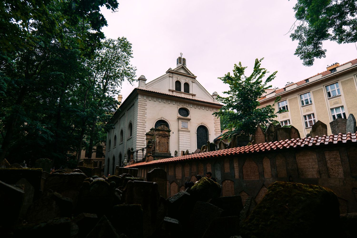 A row of historic Spanish colonial style buildings with terracotta roofs and arched windows in a shaded courtyard.