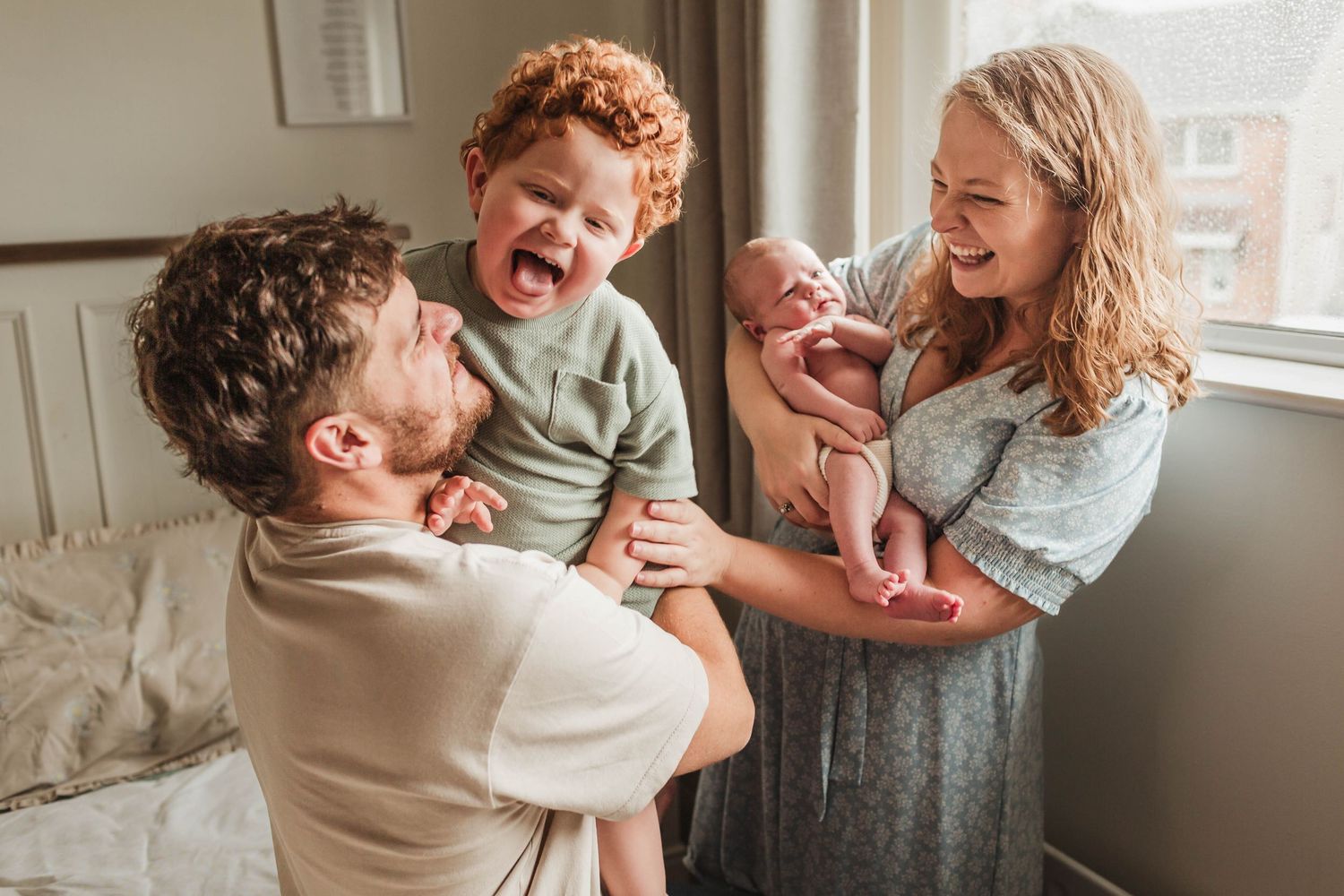 A joyful family shares a candid moment of laughter together by a window in their home.