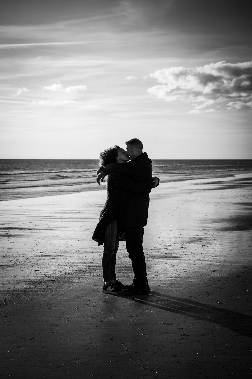 Paar steht Bauch an Bauch am Strand in Dänemark und schaut sich verliebt in die Augen, Schwarz-Weiß-Outdoor-Pärchenshooting