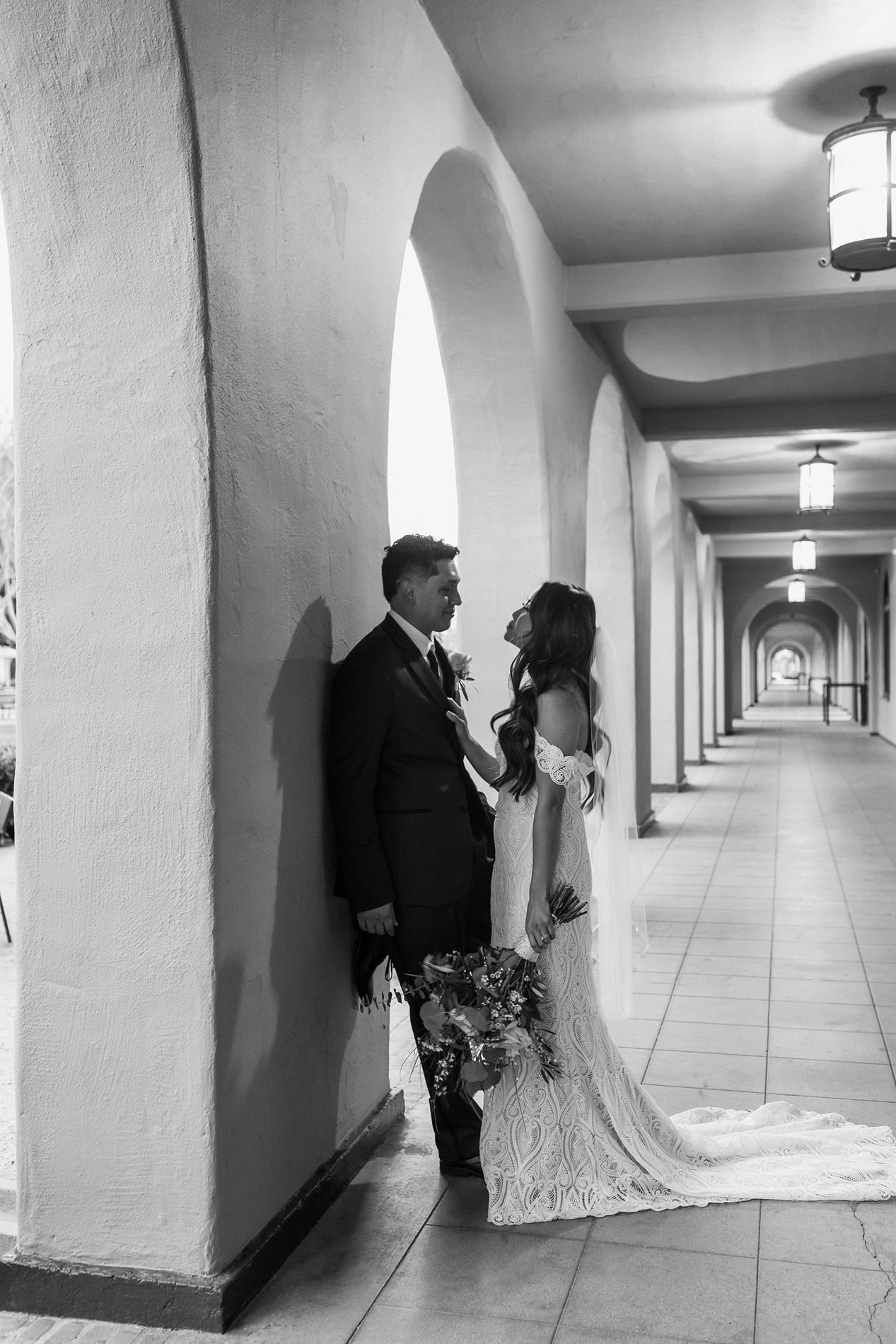 Black and white wedding photos show a couple posing against arched columns. at Liberty Station in San Diego.