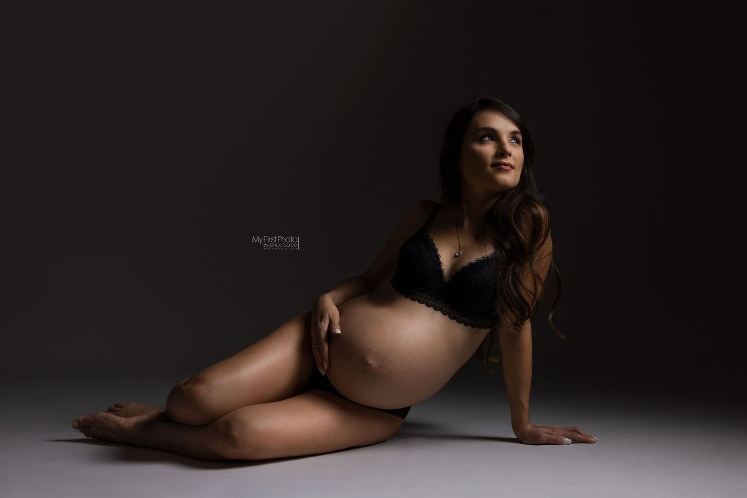 Artistic maternity silhouette against dark background with dramatic lighting.