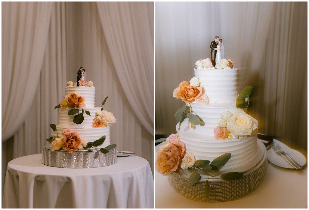 A collection of elegant white wedding cakes decorated with fresh peach and orange flowers displayed on crystal cake stands.
