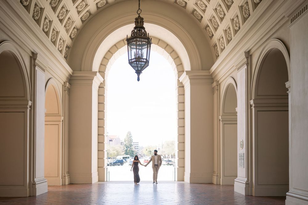 Elegant arched colonnade hallway with ornate ceiling details and hanging lantern in a historic building.