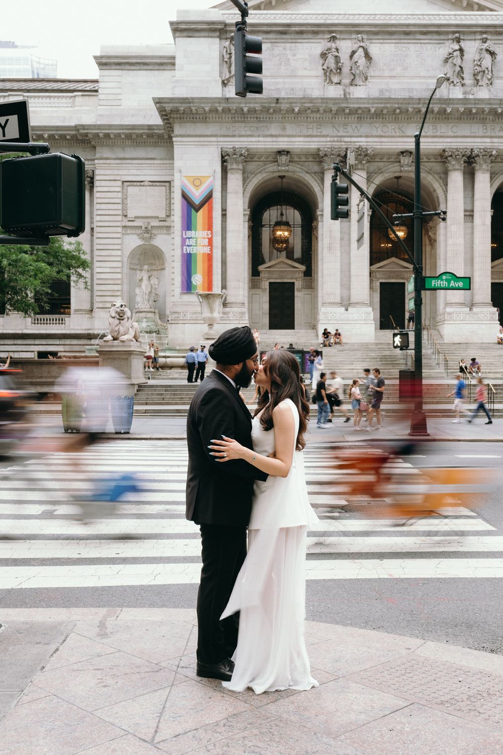 Bride and groom share a romantic moment on a busy NYC crosswalk outside the New York Public Library.