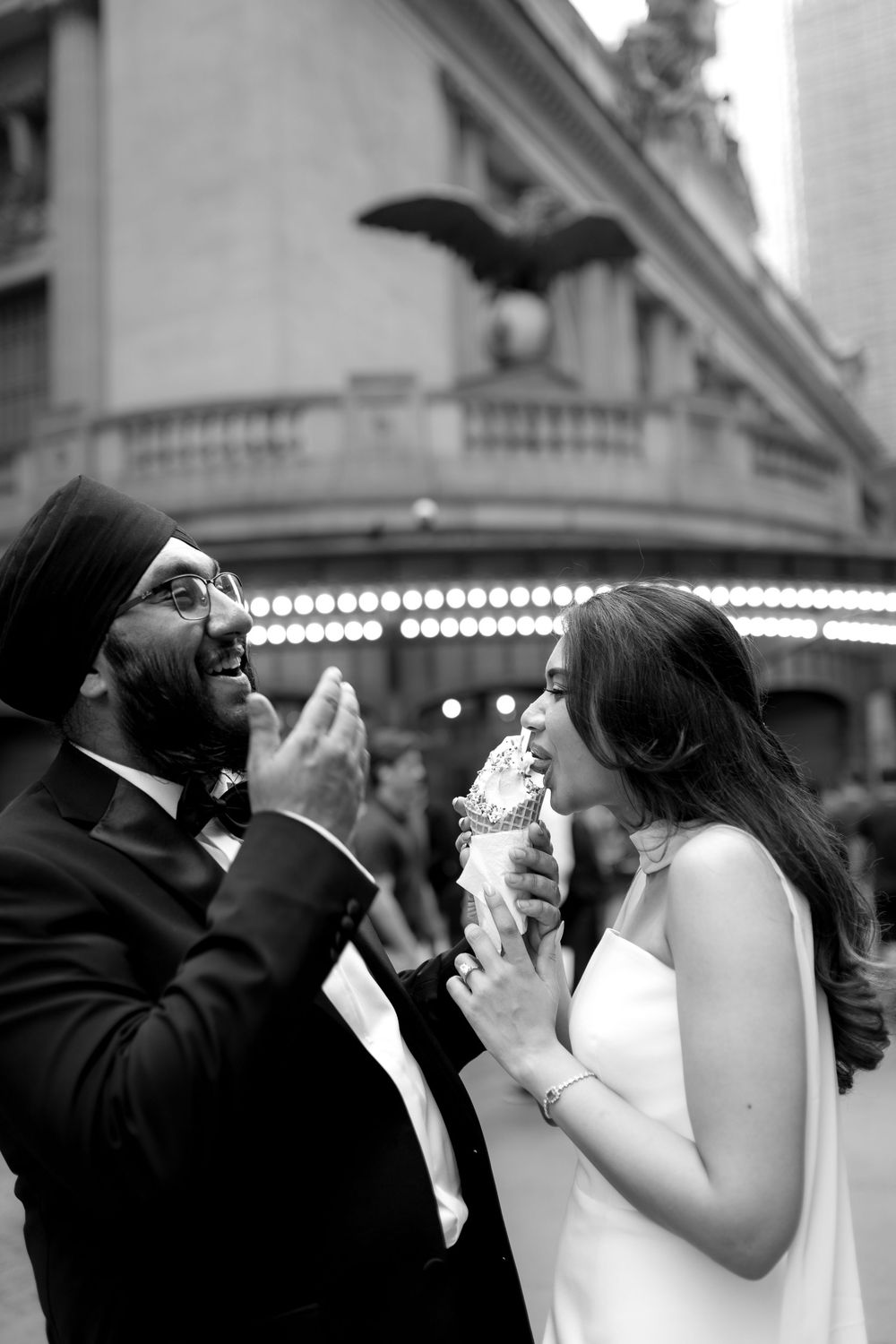 Black and white photo of newlyweds sharing ice cream outside Grand Central Terminal in NYC.