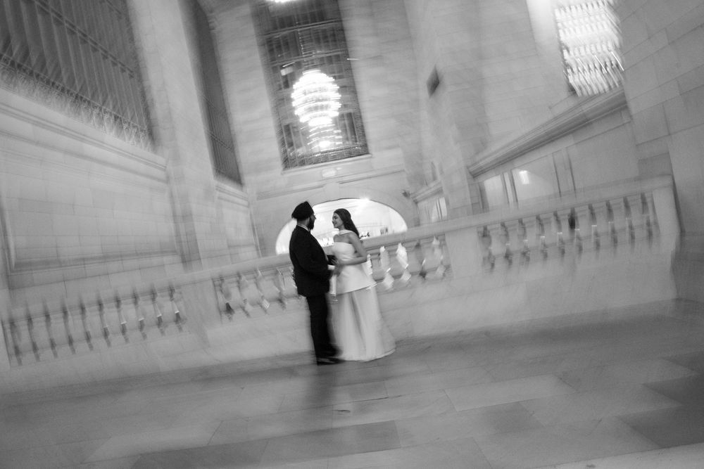 Black and white photo of a bride and groom sharing a romantic moment inside Grand Central Terminal, NYC.