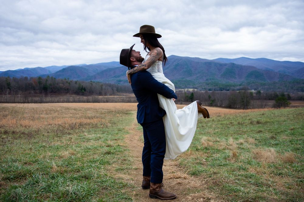 A romantic couple shares a tender moment in a scenic mountain field during a wedding photo session.