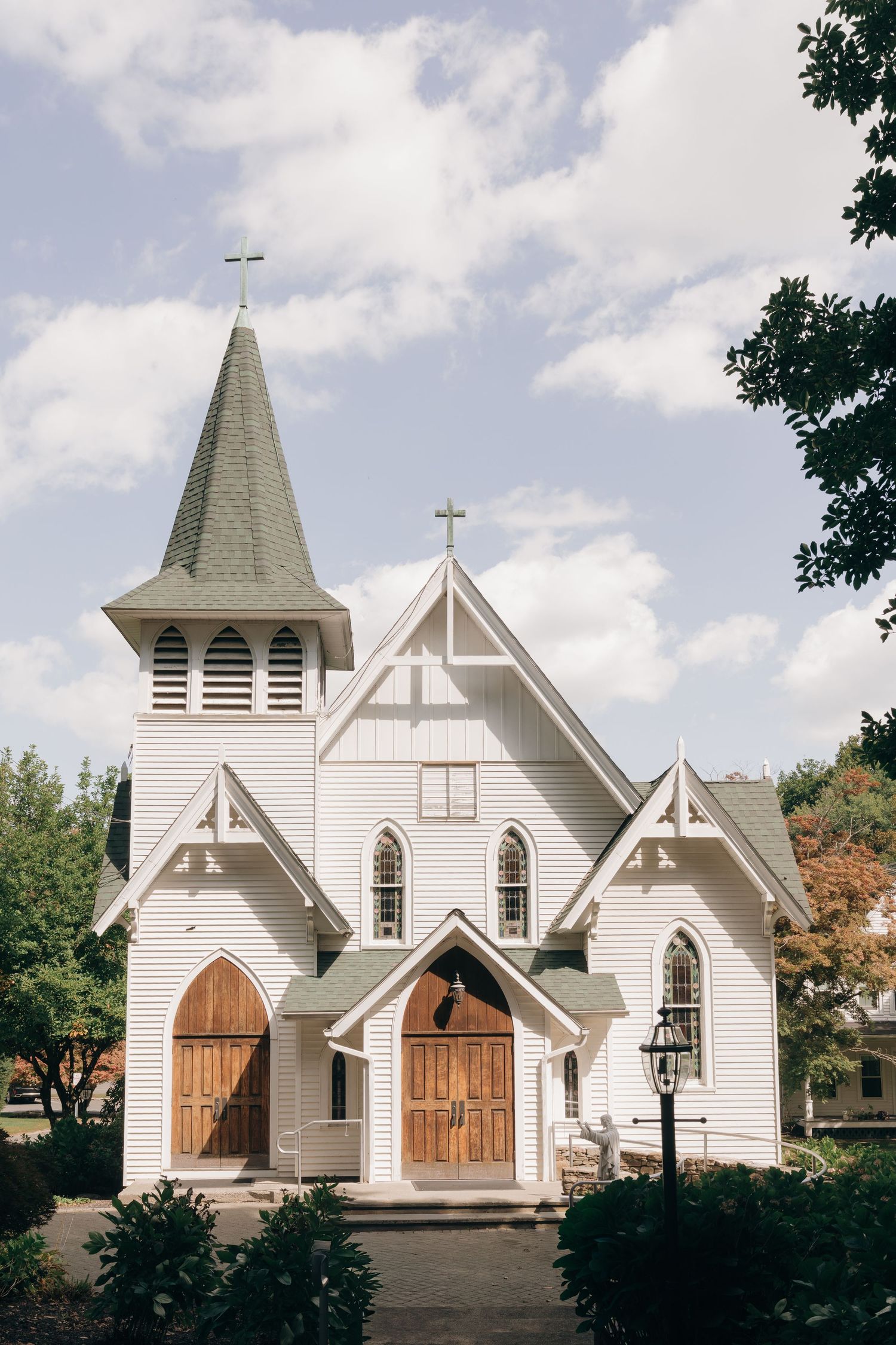 Four white wooden churches with steeples and wooden doors are shown in a panoramic sequence against a partly cloudy sky.