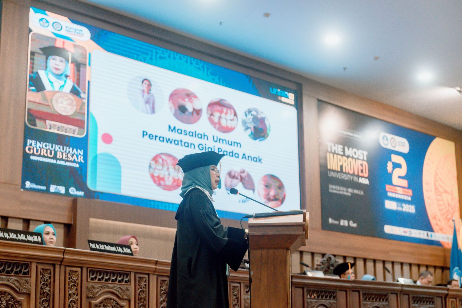 A person in a hijab stands in front of a large projection screen displaying business presentation slides in a conference room.
