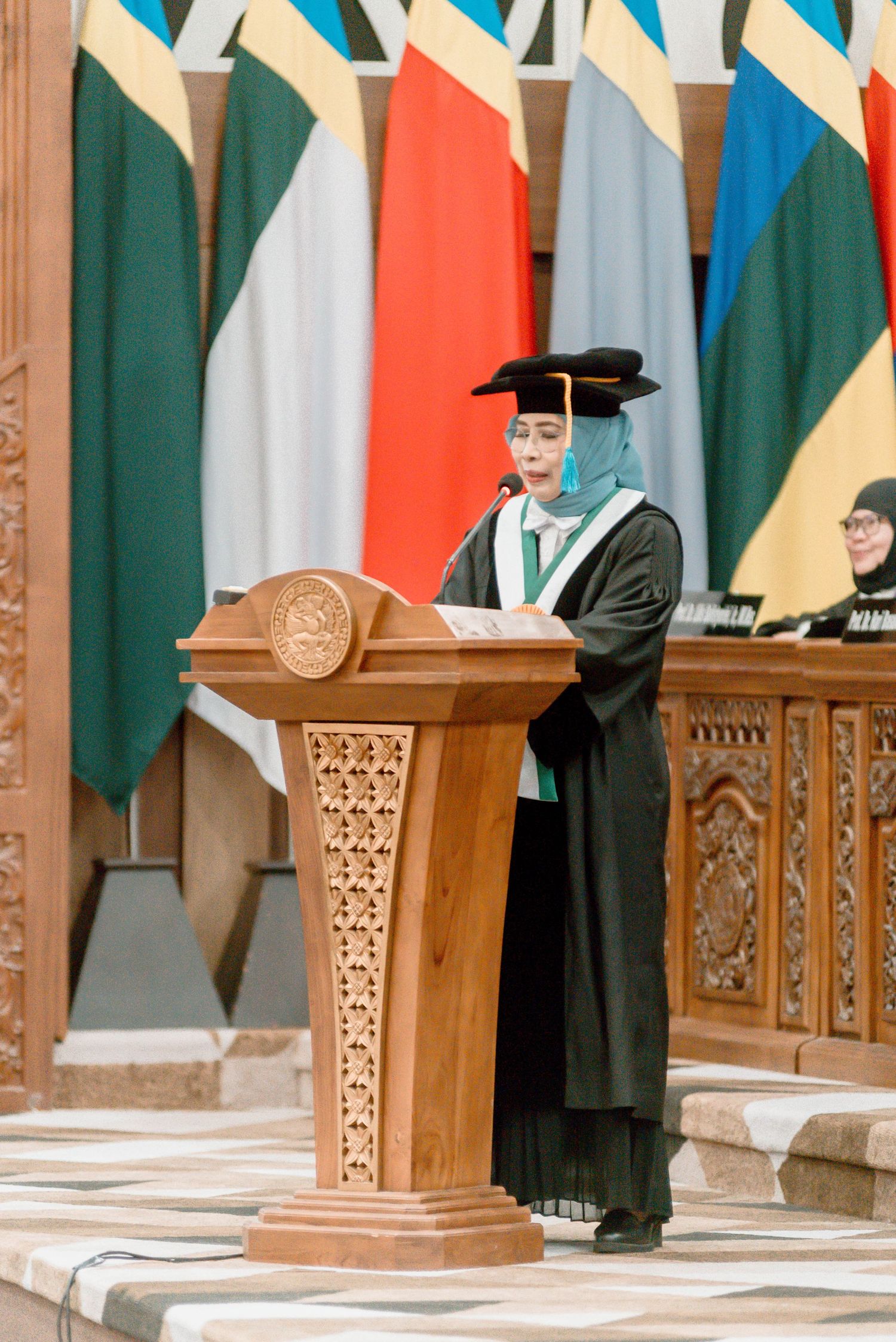 Wooden carved podiums stand in front of colorful striped fabric panels in an ornate ceremonial space.