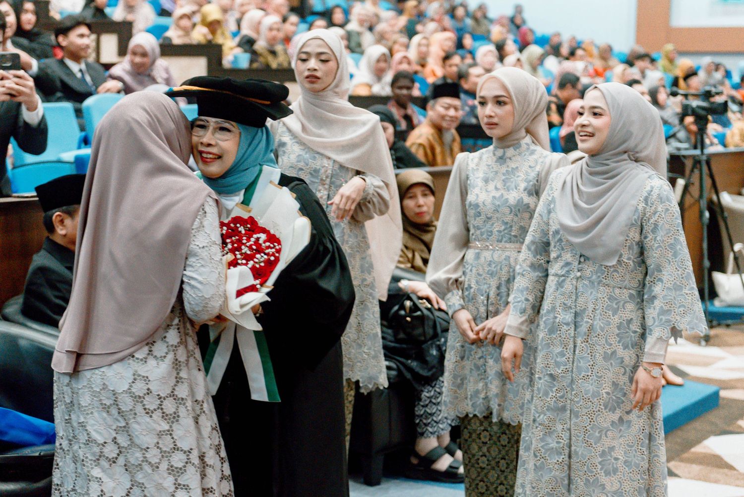 A group of people in traditional dress gather at a formal celebration event wearing elegant blue and grey attire.