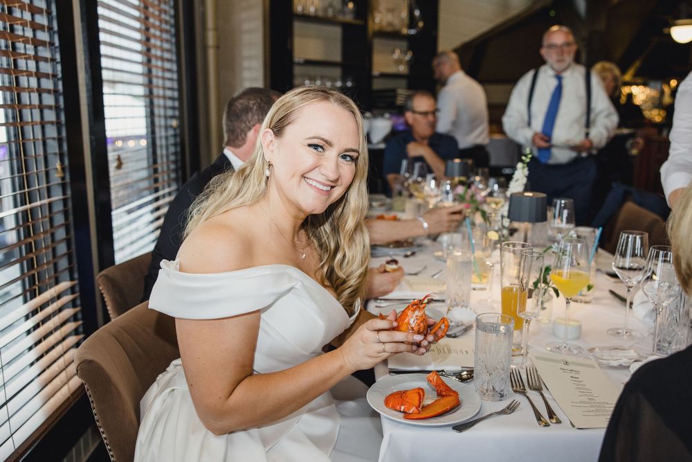 Guests enjoying a formal dining event at a restaurant with white tablecloths and window blinds.
