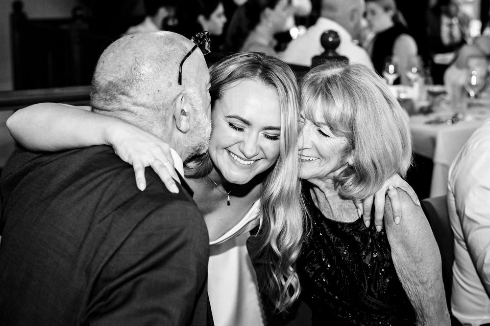 A collage of black and white candid wedding photos showing joyful moments between couples and guests at a celebration.