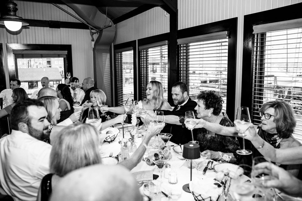 A black and white panoramic view of people dining together at a restaurant table.