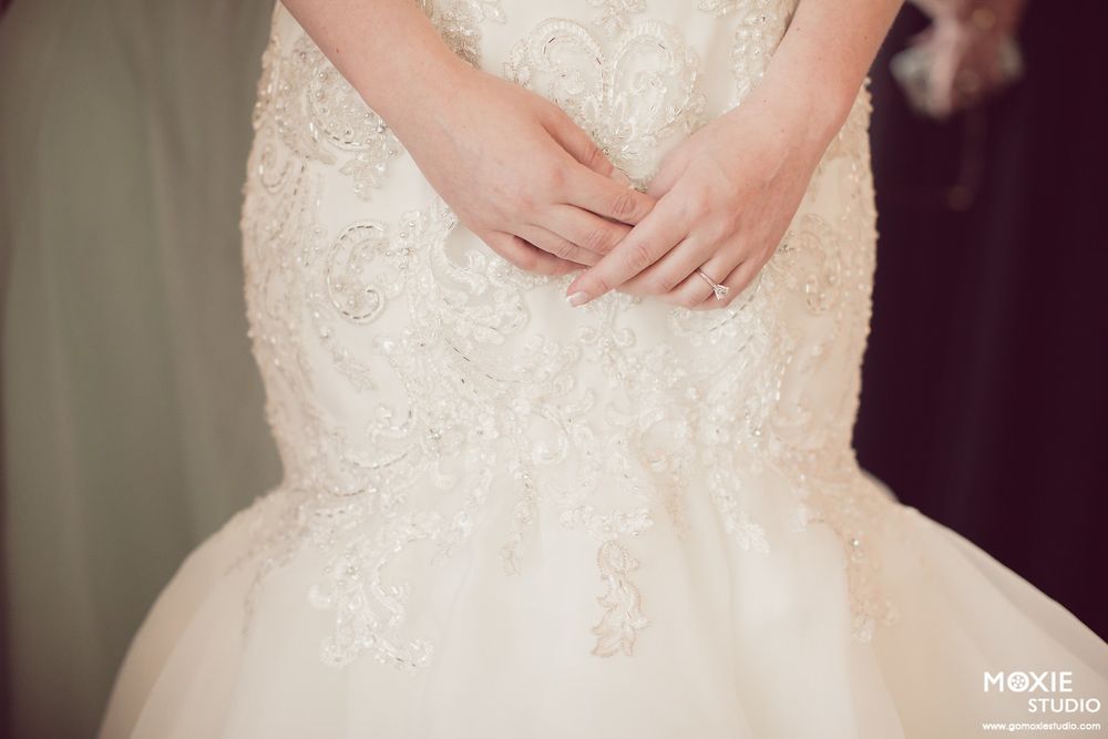 Close-up detail shot of an elegant white lace wedding dress bodice with intricate beading and embellishments.