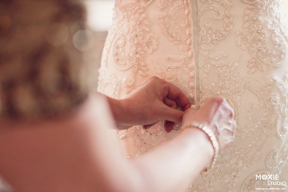 A delicate lace wedding dress detail shows intricate floral patterns and beading in soft ivory tones.