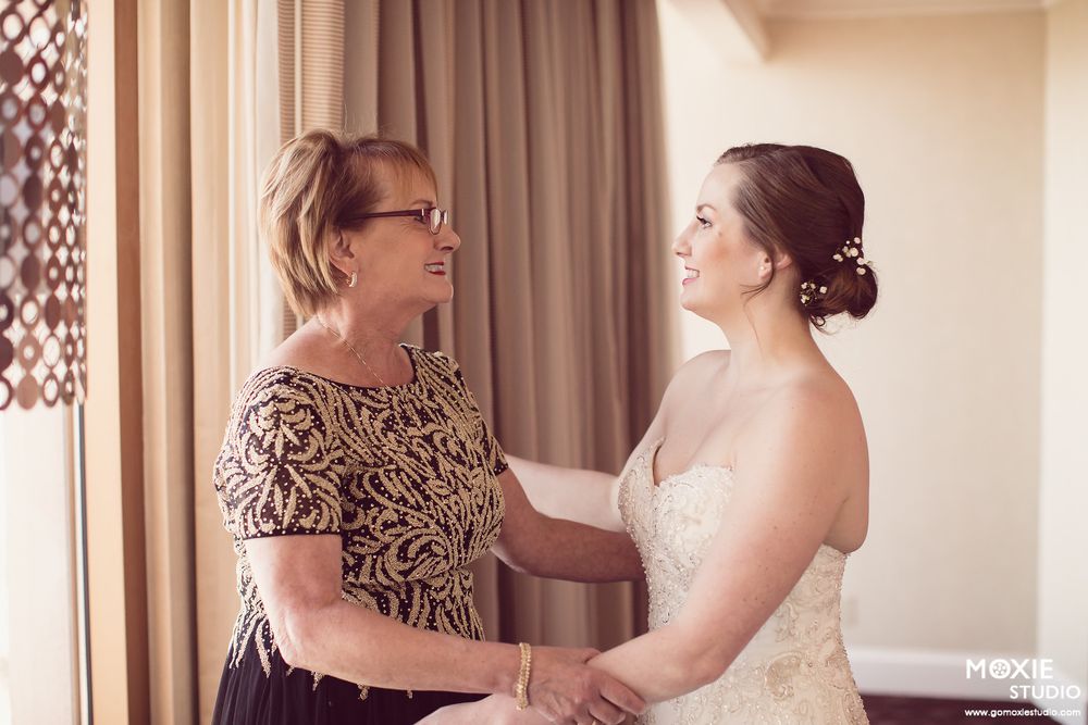 A tender moment between two women in formal attire sharing an emotional pre-wedding moment.