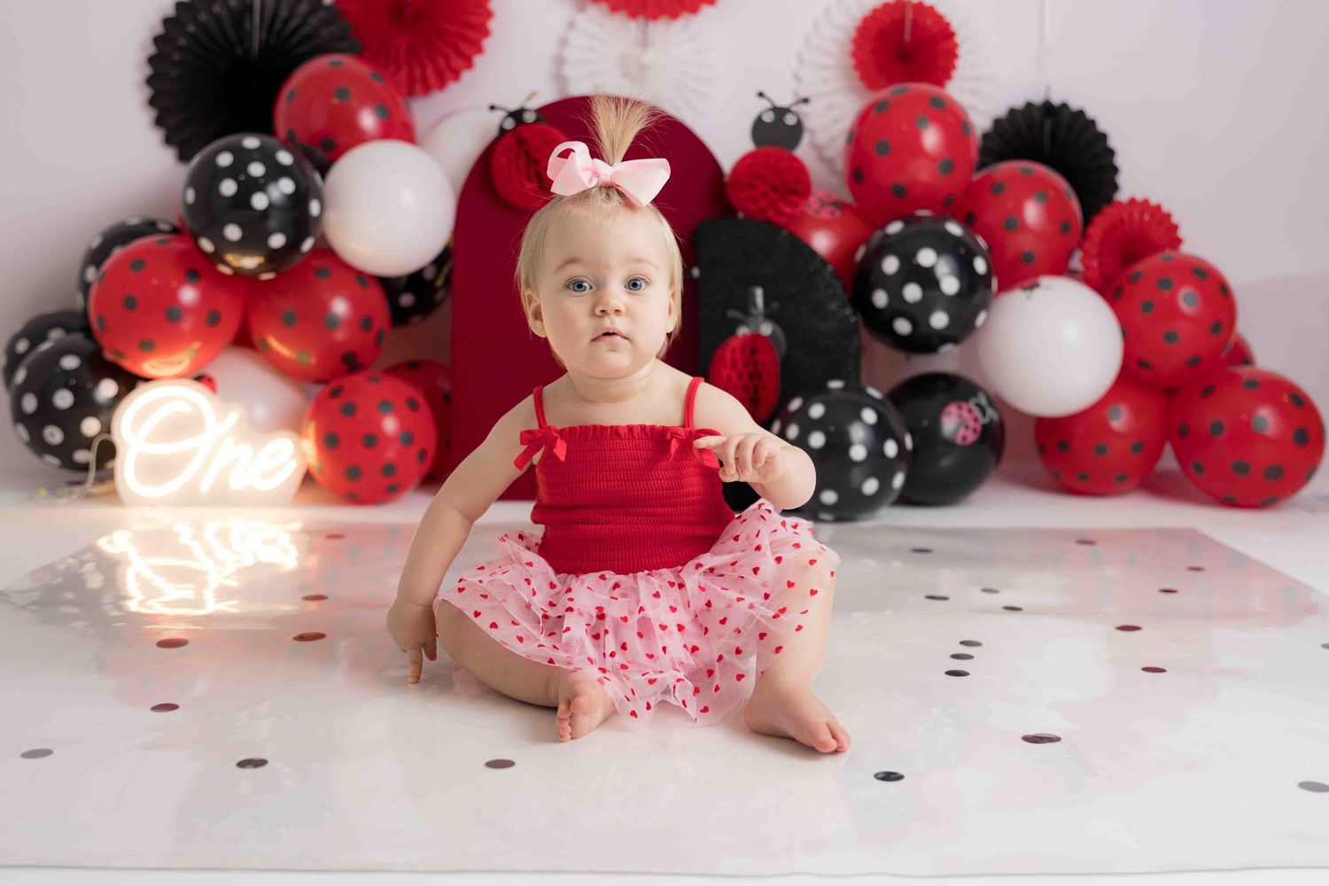 A festive balloon arch display in red, black and white colors creates a celebratory backdrop for a special occasion.