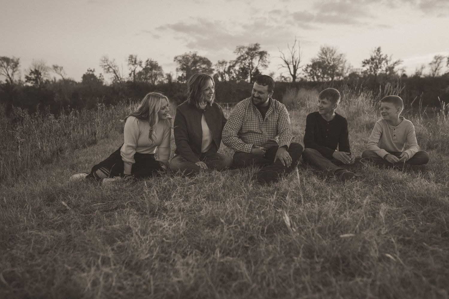 Extended family sitting close in a Kansas field – black and white family portrait with timeless storytelling