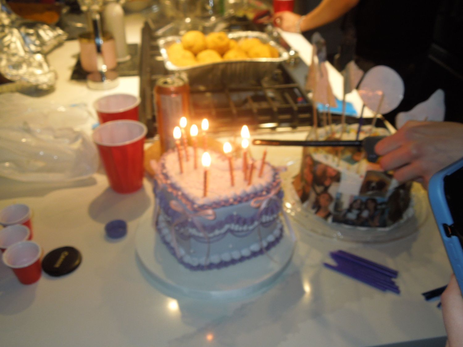Blurry photo of a purple birthday cake with lit candles