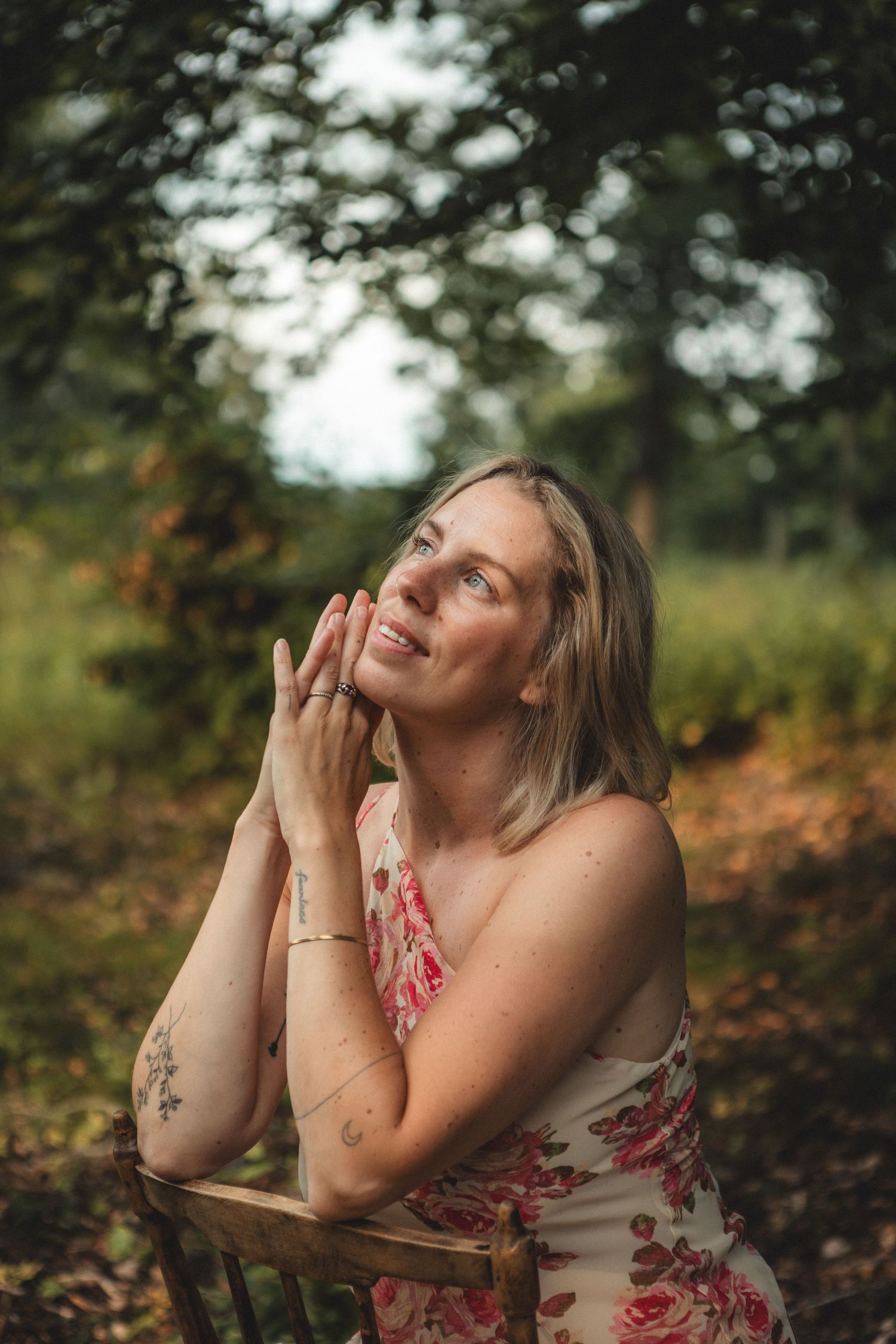 Person in floral dress expressing joy in autumn forest setting.