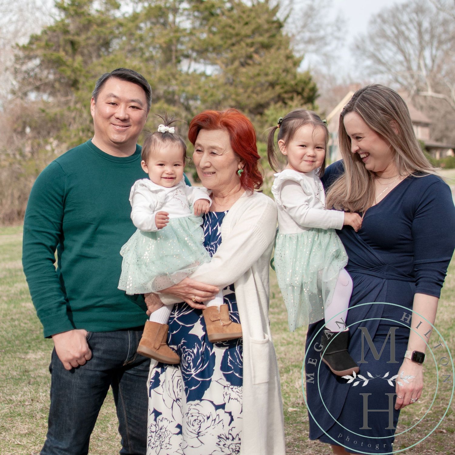 Photo of a family of five wearing coordinated outfits poses together outdoors against a natural landscape in springtime.