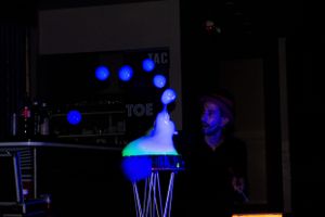 Dark nightclub setting with blue lighting and silhouetted figures.