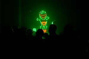 Green neon stick figure animations displayed on dark background during performance.