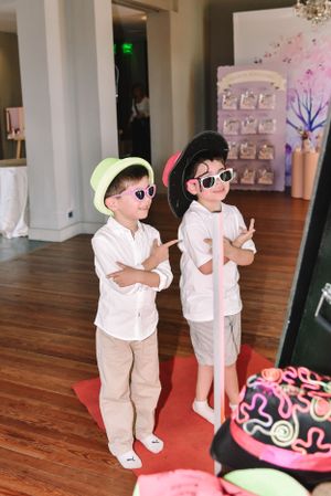 Two young party guests wearing matching white shirts and sunglasses strike cool poses.