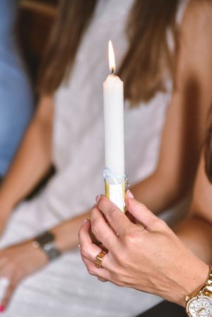 Hands holding white candles during a ceremonial event.