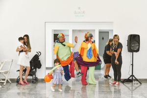 People dancing and celebrating at a lively indoor party with colorful outfits and music speakers.