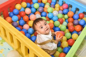 Colorful ball pit filled with multicolored plastic balls and a happy child playing.