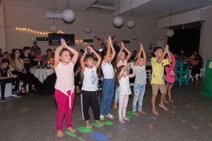 Group of children dancing with raised arms at an indoor party celebration.