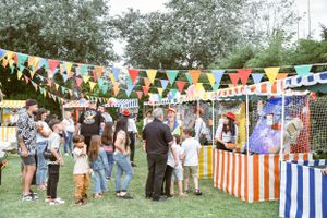 Outdoor carnival or fair with colorful striped booths and bunting decorations.