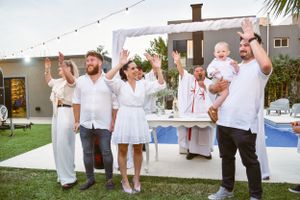 Group of people in white attire celebrating at an outdoor event.