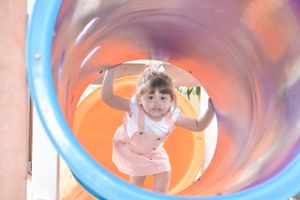 View through a blue tube slide at a playground.