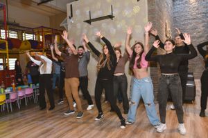 A group of energetic people jumping and celebrating together in a party venue with festive lighting.