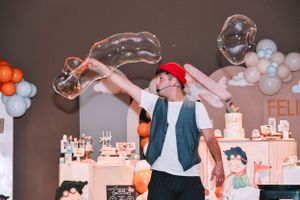 Party scene with pink and blue balloon decorations and people celebrating in a dimly lit room.
