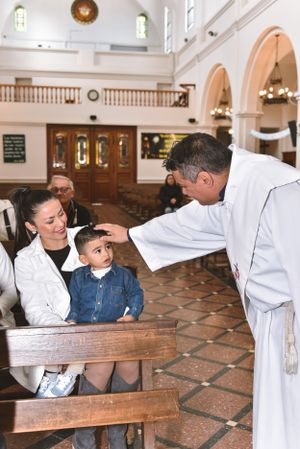 A religious ceremony taking place inside a traditional church with arched architecture and tiled floors.