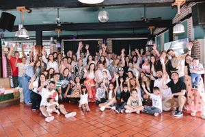 Large group celebration gathering in a rustic indoor venue with brick walls and festive atmosphere.