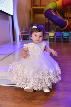 White lace dress flowing on purple-lit wooden floor during special event.