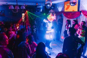 Nightclub scene with colorful blue and pink lighting creating an energetic party atmosphere.