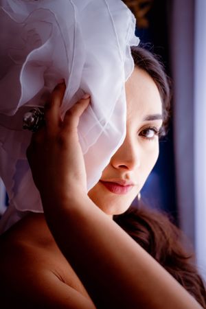 Close-up bridal portrait showing delicate feathered headpiece and soft bridal makeup, during a bridal portrait session.