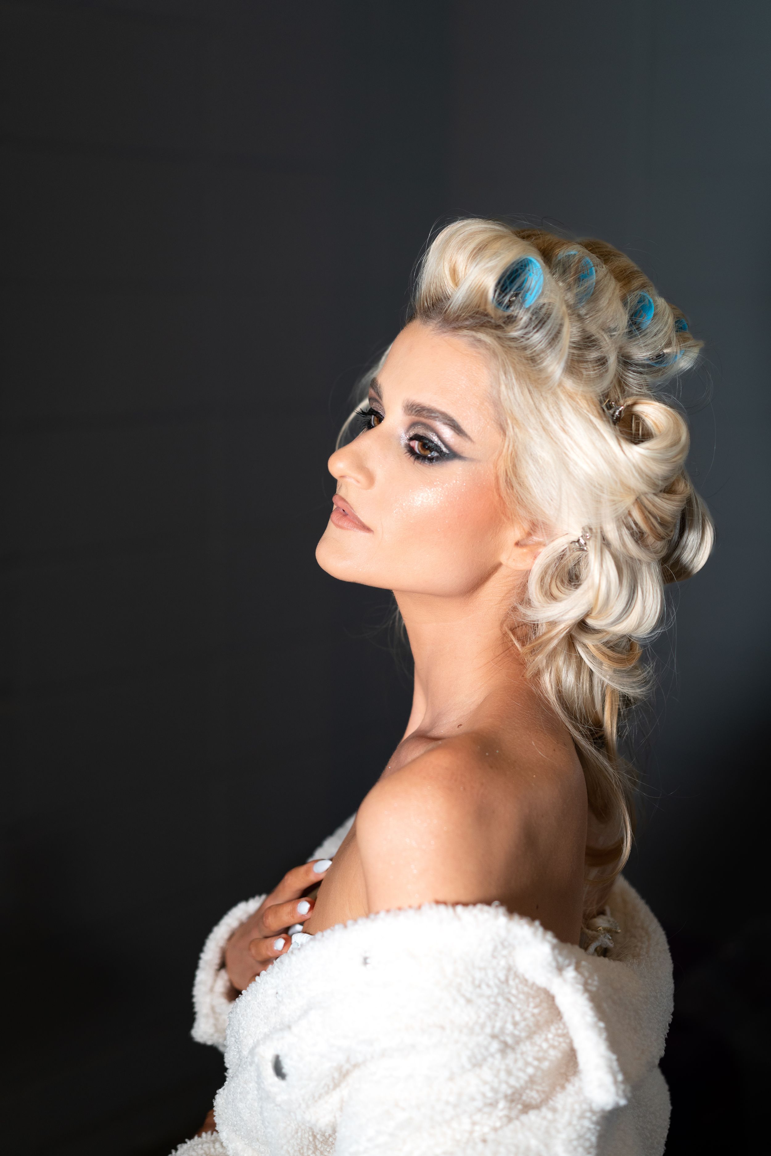 Glamorous portrait with vintage-inspired hairstyle and dramatic makeup against dark background, during a bridal portrait session.