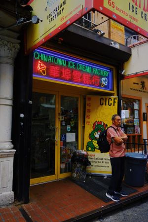 Colorful neon sign reads 'Chinatown Ice Cream Factory' above storefront entrance on city sidewalk at dusk.