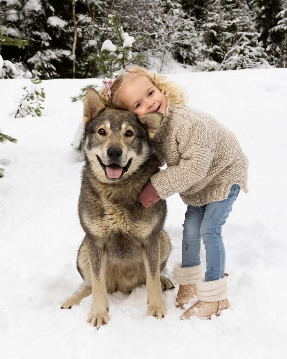 Jente som holder rundt en stor hund i snøen i skogen i Mandal