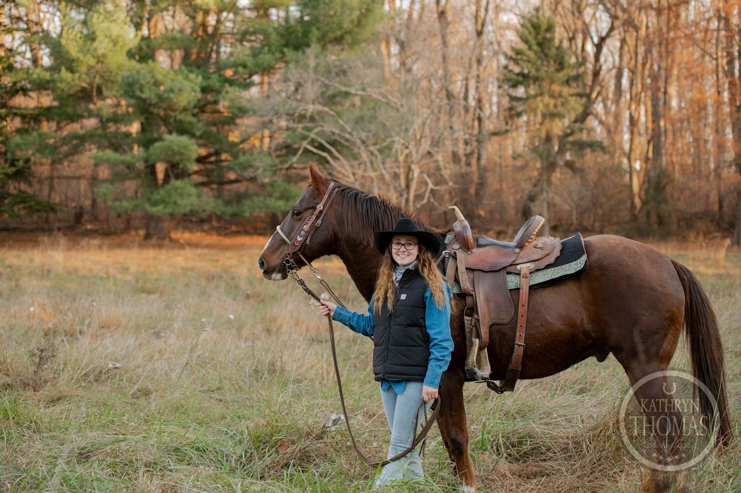 Brown horse with western tack standing in autumn field with handler.