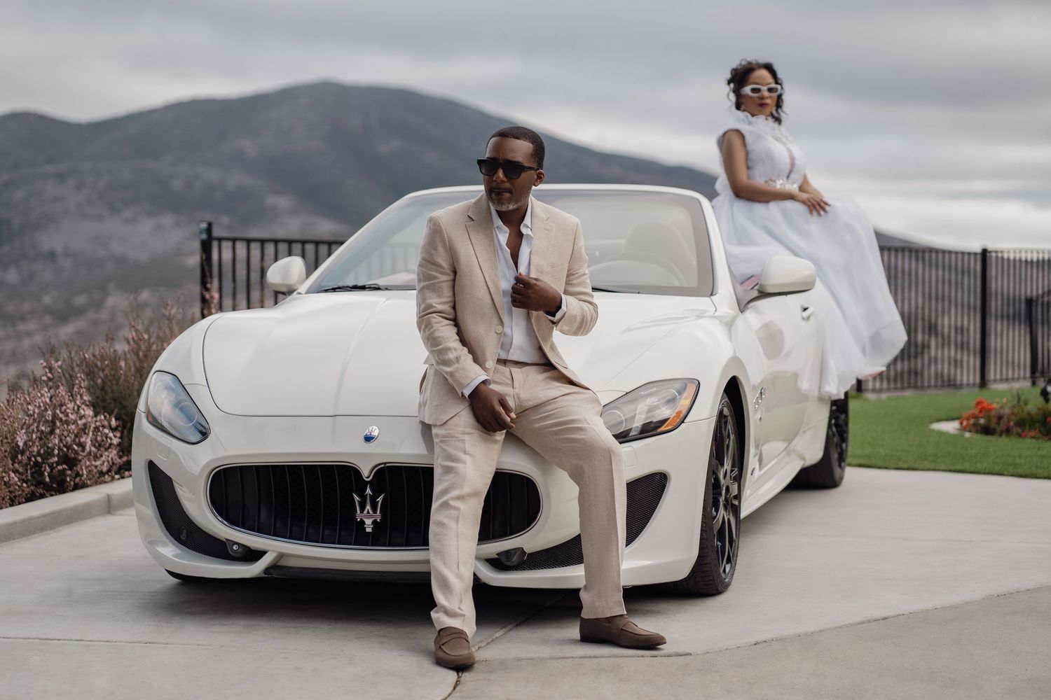Luxury wedding photoshoot featuring a white Maserati sports car against a mountain backdrop.