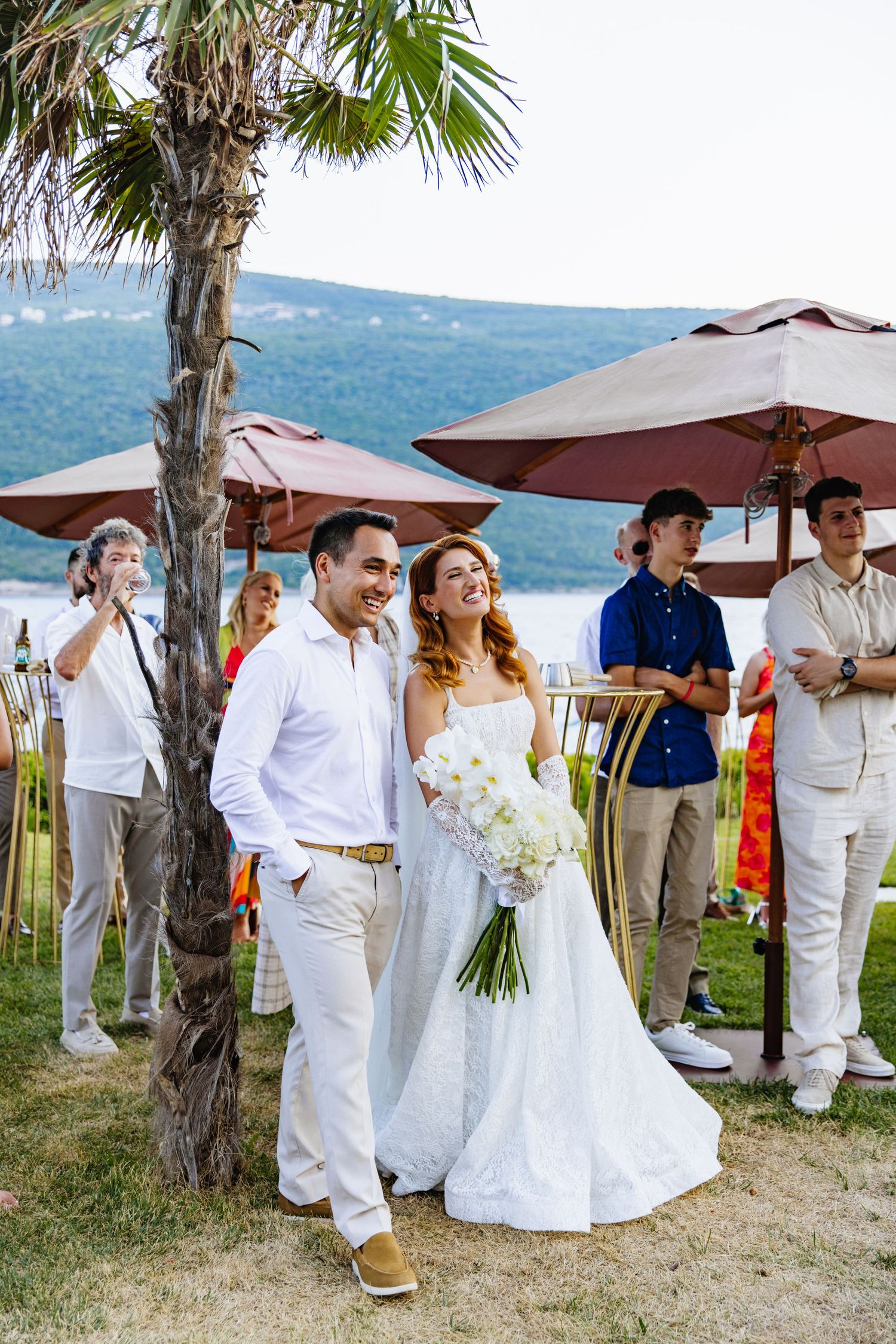 Outdoor wedding celebration under palm trees with stunning mountain views in the background.